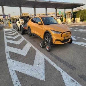 שירותי גרר דולי לרכב חשמלי צהוב על כביש פתוח